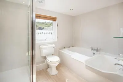 a bathroom with a toilet and a tub and a sink at The Old Farmhouse in Balloch