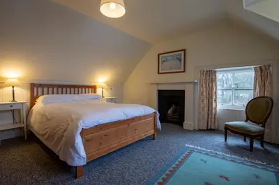 a bedroom with a bed and a chair and a fireplace at Rhunacairn in Oban