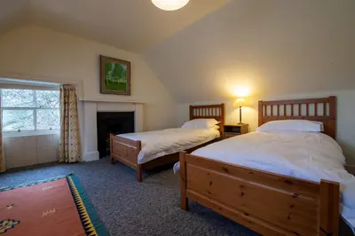 a bedroom with two beds and a fireplace at Rhunacairn in Oban