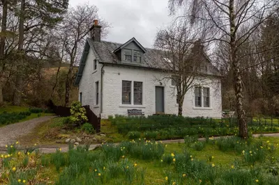 an old white house in a field of flowers at Rhunacairn in Oban