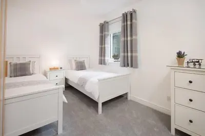 a white bedroom with two beds and a window at Ardchyle House in Killin