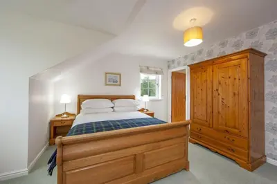 a bedroom with a large bed and a wooden cabinet at Branter Lodge in Strachur