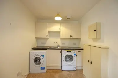 a kitchen with a washing machine and a washer at Branter Lodge in Strachur