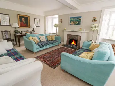 a living room with two blue couches and a fireplace at Ardchattan Manse in Oban