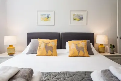 a bedroom with a bed with yellow pillows and two lamps at Gaidrew Cottage in Drymen
