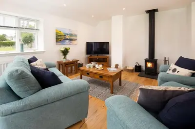 a living room with two blue couches and a fireplace at Gaidrew Cottage in Drymen