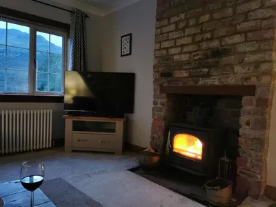 a living room with a fireplace and a television at Arrochar Fern Cottage with Wood Burner & Loch View in Arrochar