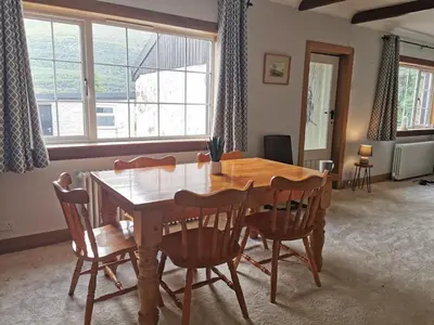 a dining room with a wooden table and chairs at Arrochar Fern Cottage with Wood Burner & Loch View in Arrochar
