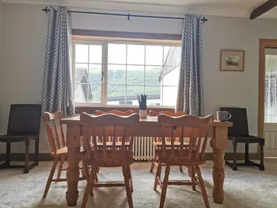 a dining room table with four chairs and a window at Arrochar Fern Cottage with Wood Burner & Loch View in Arrochar