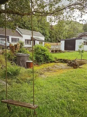 a garden with a bench in a yard with a house at Arrochar Fern Cottage with Wood Burner & Loch View in Arrochar