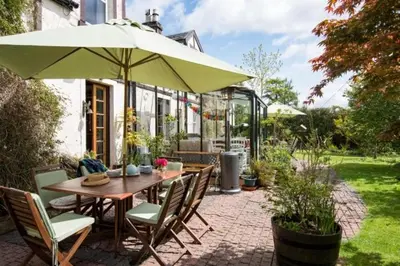 a table and chairs with an umbrella on a patio at Strone House in Helensburgh