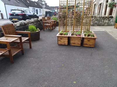 a patio with tables and chairs and plants in wooden crates at CRAIGLEA HEATHER in Killin