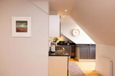 an attic kitchen with a counter and a clock on the wall at JOIVY Luxury Flat near Edinburgh Castle in Edinburgh