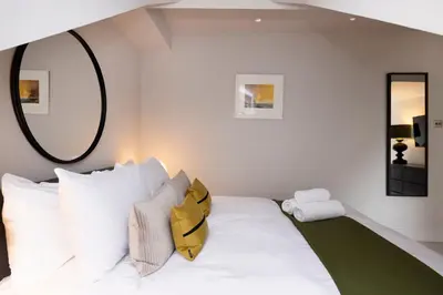 a bedroom with a white bed with a yellow backpack on it at JOIVY Luxury Flat near Edinburgh Castle in Edinburgh