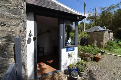 a small cottage with a door and some plants at Yewtree Cottage - 'The Art House' and Garden in Hunters Quay