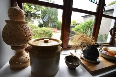 a window sill with vases and a jar on a table at Yewtree Cottage - 'The Art House' and Garden in Hunters Quay