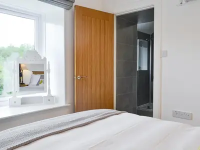 a bedroom with a bed and a mirror and a shower at Boatman's Cottage At Invernian Mor in Inverinan Beg