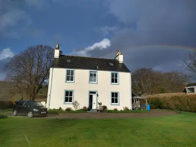 a white house with a car parked in front of it at Kirkland House B&B in Tarbert