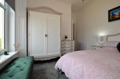 a white bedroom with a bed and a dresser at Findhorn Upper Apartment in Kames