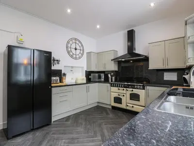 a kitchen with white cabinets and a black refrigerator at Argyle House in Rothesay