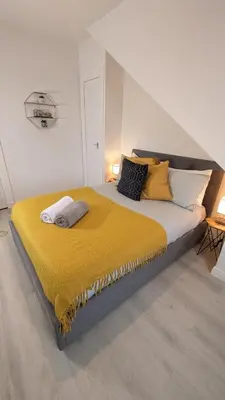 a bedroom with a large bed with yellow sheets and pillows at Lovely 2 Bedroom Apartment in Central Location in Greenock
