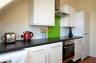a kitchen with white cabinets and a black counter top at Arran View in Lochgilphead
