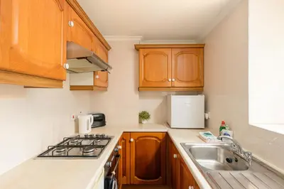 a kitchen with wooden cabinets and a sink at Dean Village Hideaway by Calton Living in Edinburgh