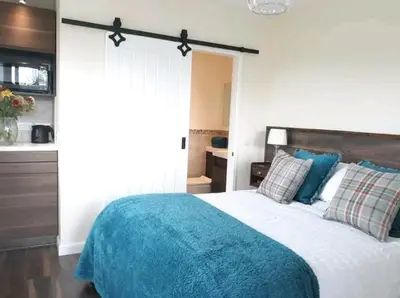a bedroom with a bed with a blue blanket at Romantic Rural Lodge - Private Outdoor Kitchen & Cosy Covered Lounge - Perth and Kinross - Hot Tub not included in Crook of Devon