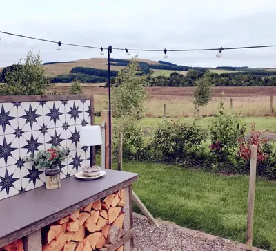 a table in a garden with a view of a field at Romantic Rural Lodge - Private Outdoor Kitchen & Cosy Covered Lounge - Perth and Kinross - Hot Tub not included in Crook of Devon