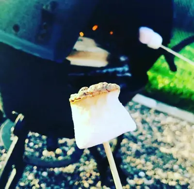 a piece of food on a stick in front of a grill at Rural Private Lodge - With Hot Tub - Outdoor Kitchen and Covered Lounge for Two in Crook of Devon