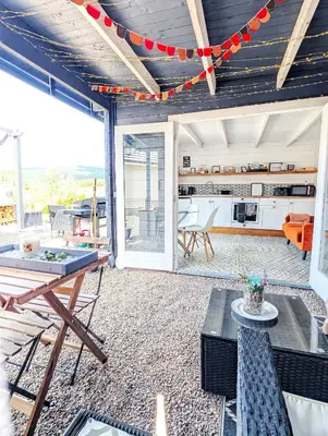 a living room with a table and a kitchen at Rural Private Lodge - With Hot Tub - Outdoor Kitchen and Covered Lounge for Two in Crook of Devon