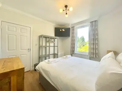 a bedroom with a large white bed and a window at Clyde Villa in Glasgow
