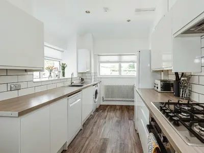 a white kitchen with a sink and a stove at Holmbyre Smithy in Dalry