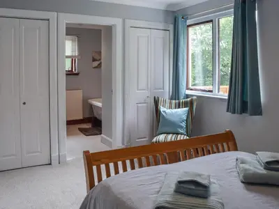 a bedroom with a bed and a window and a chair at Tamarchan Lodge in Ballachulish