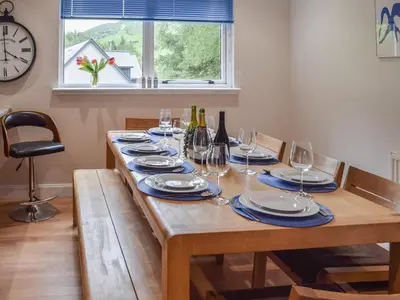 a wooden table with wine glasses and wine bottles at Tamarchan Lodge in Ballachulish