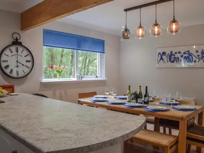 a dining room with a table and a clock at Tamarchan Lodge in Ballachulish