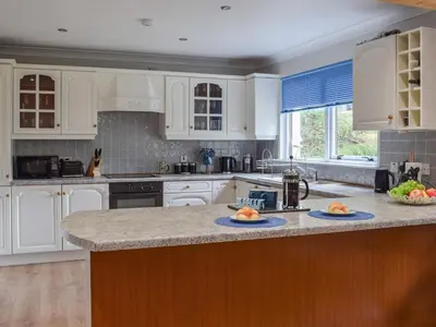 a kitchen with white cabinets and a granite counter top at Tamarchan Lodge in Ballachulish