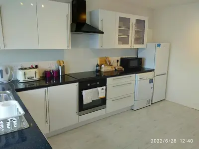 a kitchen with white cabinets and a black stove top oven at Cottage with Panoramic Views in Kirk of Shotts