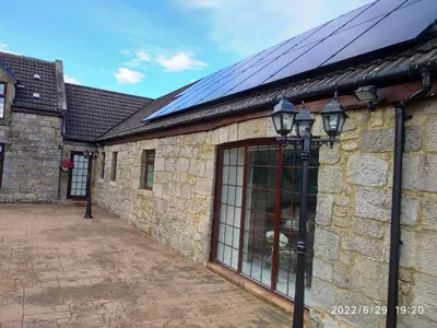 a stone building with solar panels on it at Cottage with Panoramic Views in Kirk of Shotts