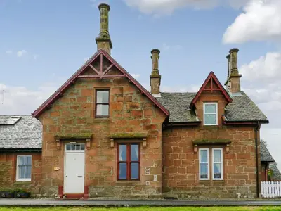 an old brick house with two chimneys on top at Bay View in Brodick
