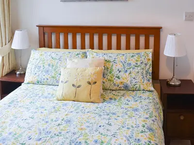 a bed with two lamps and a pillow on it at Bay View in Brodick