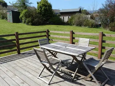 a wooden table and two chairs on a deck at Bay View in Brodick