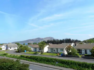 a row of houses on a street with a mountain in the background at Larkfield in Lamlash