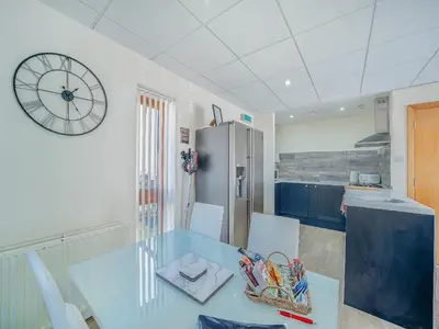 a kitchen with a table and a clock on the wall at 1 Ladyknowe - Uk39970 in Moffat