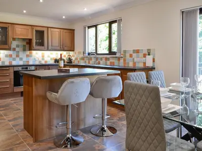a kitchen with a bar with chairs and a table at Park Lane in Auldgirth