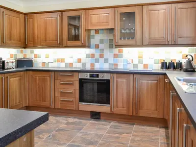 a kitchen with wooden cabinets and a stove top oven at Park Lane in Auldgirth