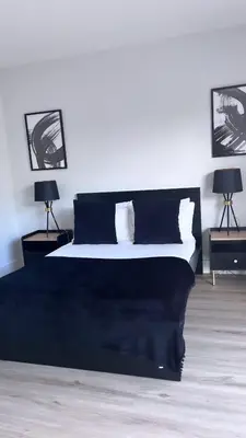a bedroom with a black and white bed with two lamps at 3 Bedroom House Near City Centre Glasgow Sleeps 7 in Glasgow