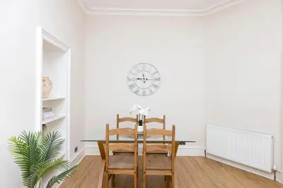 a dining room with a table and chairs and a clock at JOIVY Chic Apartment near Stockbridge Market in Edinburgh