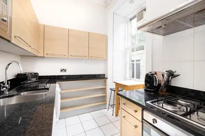 a kitchen with white cabinets and black counter tops at JOIVY Chic Apartment near Stockbridge Market in Edinburgh