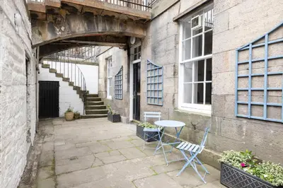 a patio with a table and chairs next to a building at JOIVY Chic Apartment near Stockbridge Market in Edinburgh